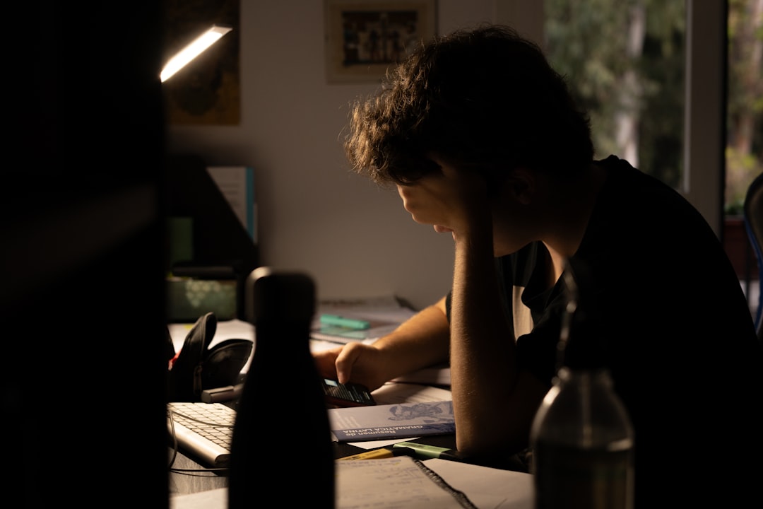Student sitting with a notebook and phone, thinking through a homework problem