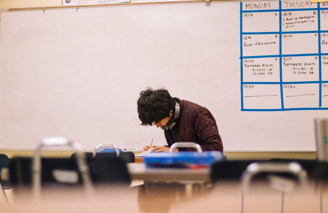 Student writing notes alone at a desk while studying for an oral exam